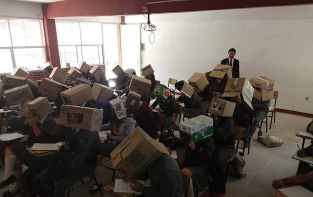 Para evitar que se copien profesor tapa la cabeza de sus alumnos con cajas de cartón